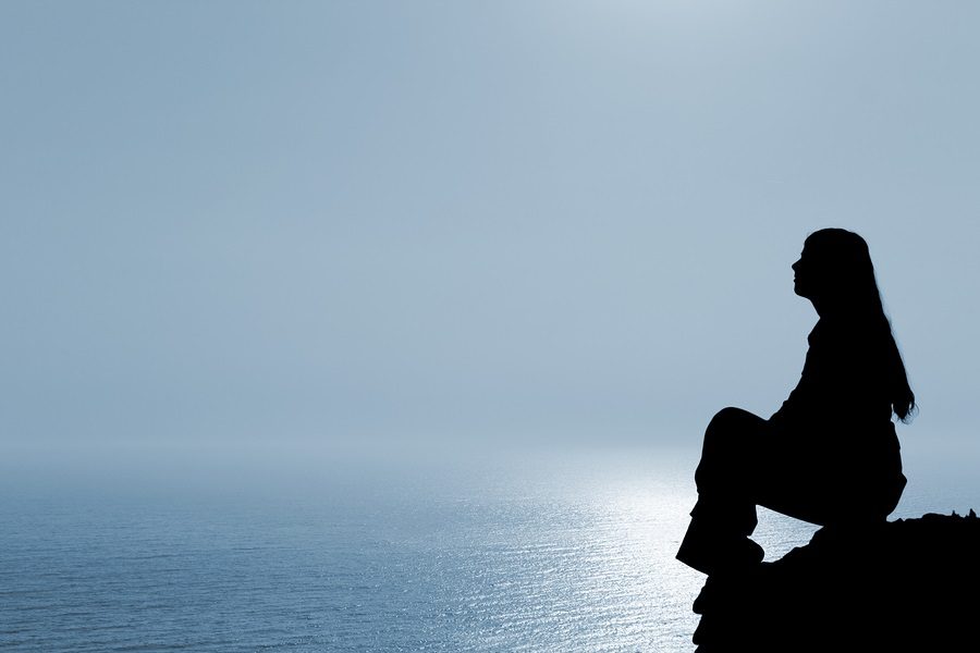 Meditating woman silhouette against seascape.