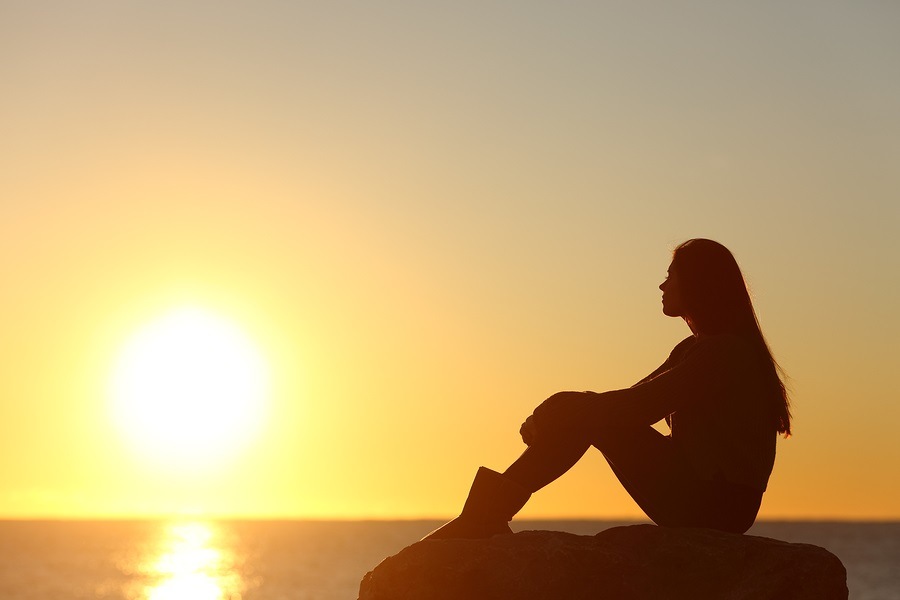 Profile of a woman silhouette watching sun on the beach at sunset